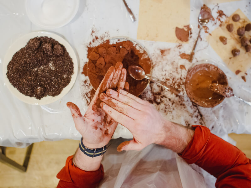 A top down of someone hand rolling truffles in a chocolate class.